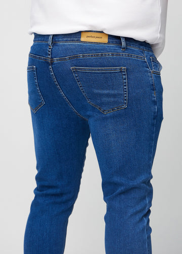 Close-up back view of dark blue denim slim jeans on a plus-size model showing details.