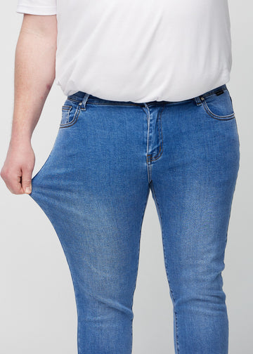 Plus-size model stretches the jeans at the thigh to show the fabric&