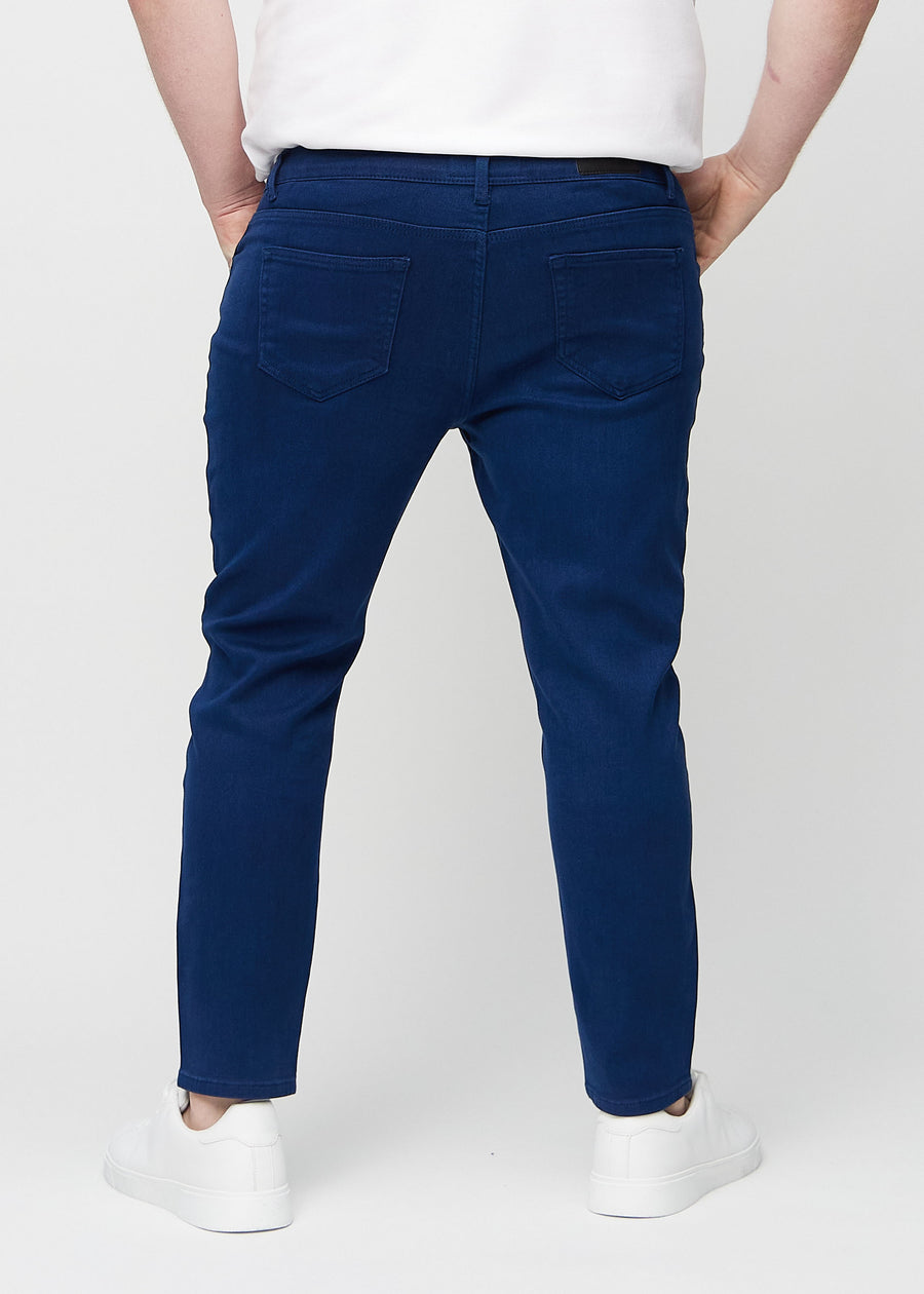 Dark blue slim jeans viewed from the back on a plus-size model to show the full product.