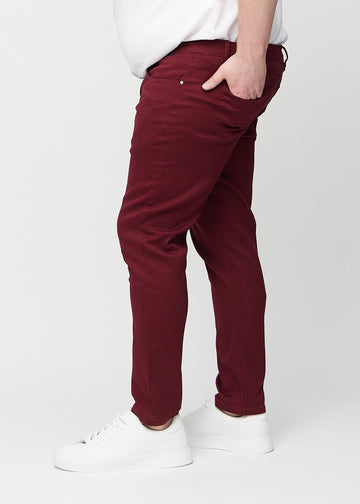 Dark red slim jeans viewed from the side on a plus-size model.