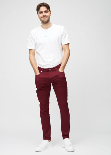 Full-length view of a model in dark red slim jeans.