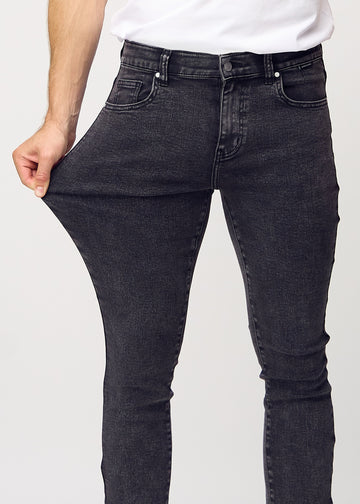 Model stretches the jeans at the thigh to show the fabric&