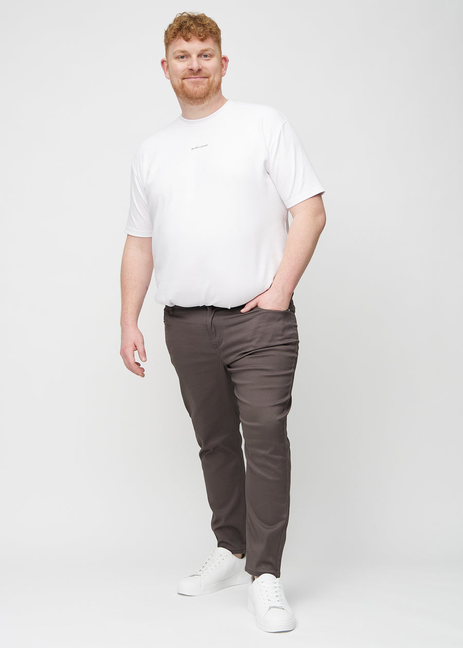 Full-length view of a plus-size model in grey-brown slim jeans.