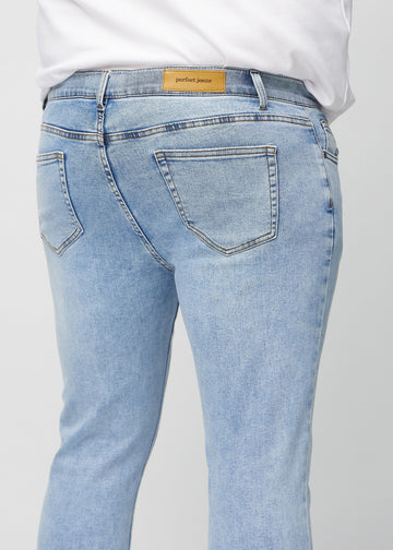 Close-up back view of light blue denim slim jeans on a plus-size model showing details.