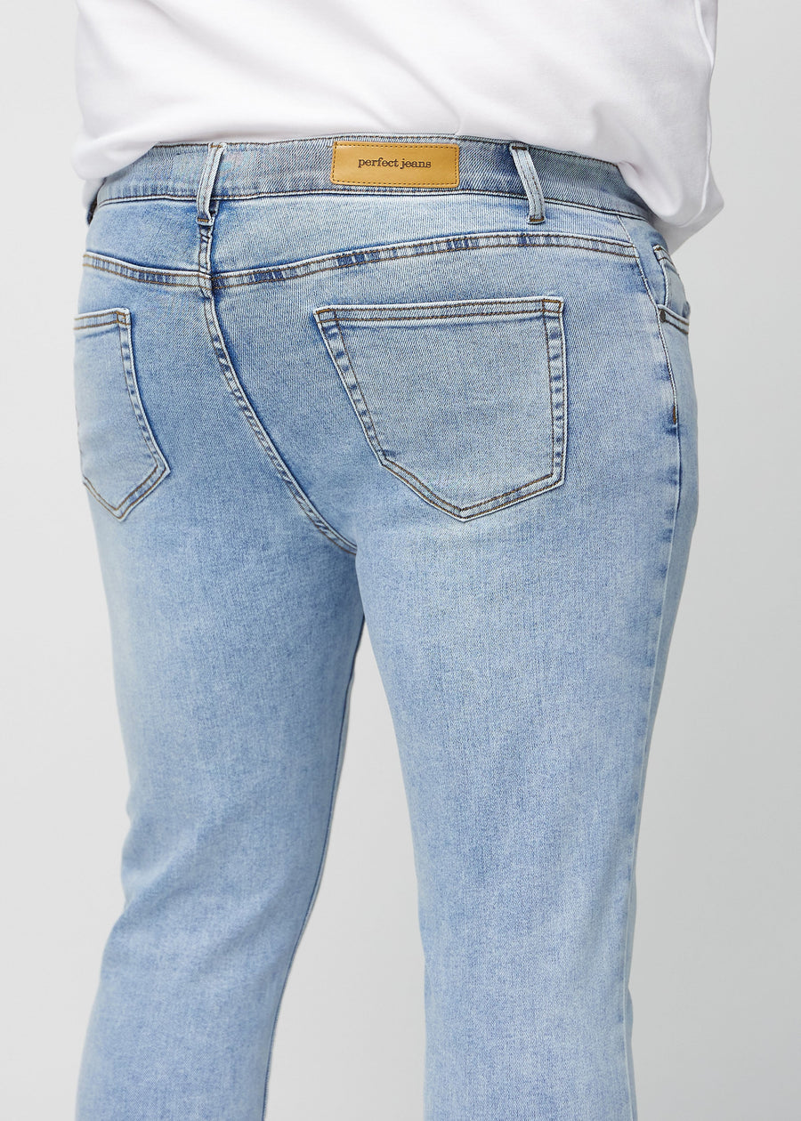Close-up back view of light blue denim slim jeans on a plus-size model showing details.