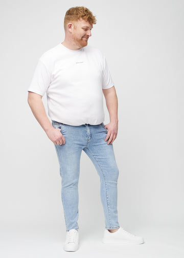 Full-length view of a plus-size model in light blue denim slim jeans.
