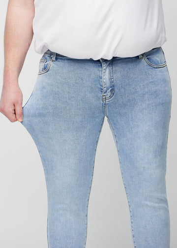 Plus-size model stretches the jeans at the thigh to show the fabric&