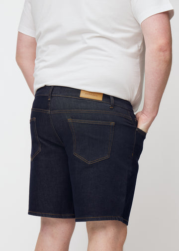 deep dark blue denim shorts for men in the colour midnights seen from the back in close-up on a plus-size model.