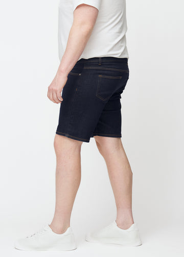 Deep dark blue denim shorts for men in the colour Midnights with a slim fit seen from the side on a plus-size model.