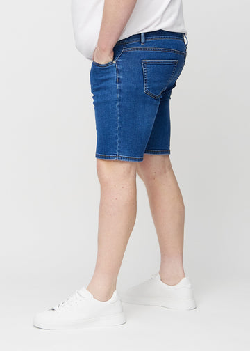 Dark denim middle-slim shorts seen from the side on a plus-size model.