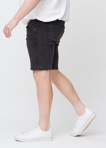 Dark grey denim middle-slim shorts seen from the side on a plus-size model.