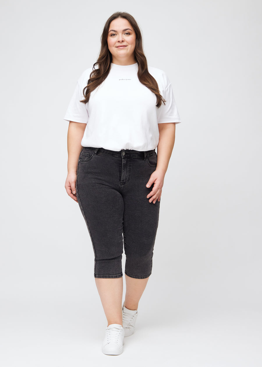 Fuldt billede af en plus-size model i mørkegrå denim skinny capris.