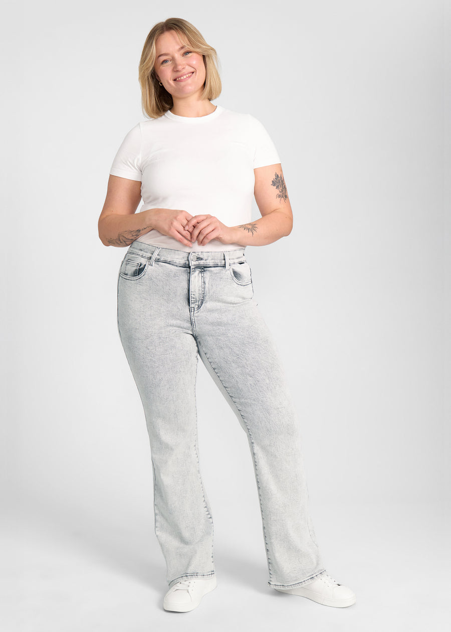 Fuldt billede af model i lysegrå denim bootcut jeans på en plus-size model.