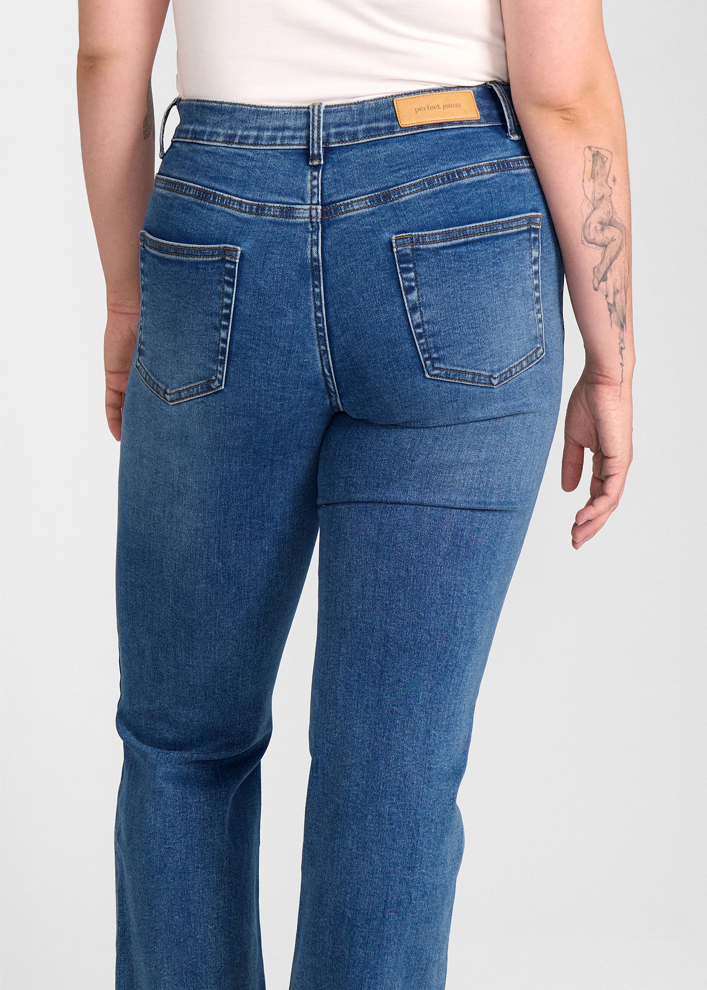 Mørkeblå denim bootcut jeans, modelnavn Oceans, som sidder tæt om hofter og lår med et let svaj fra knæet og ned, set bagfra tæt på for at vise detaljer. på en plus-size model.