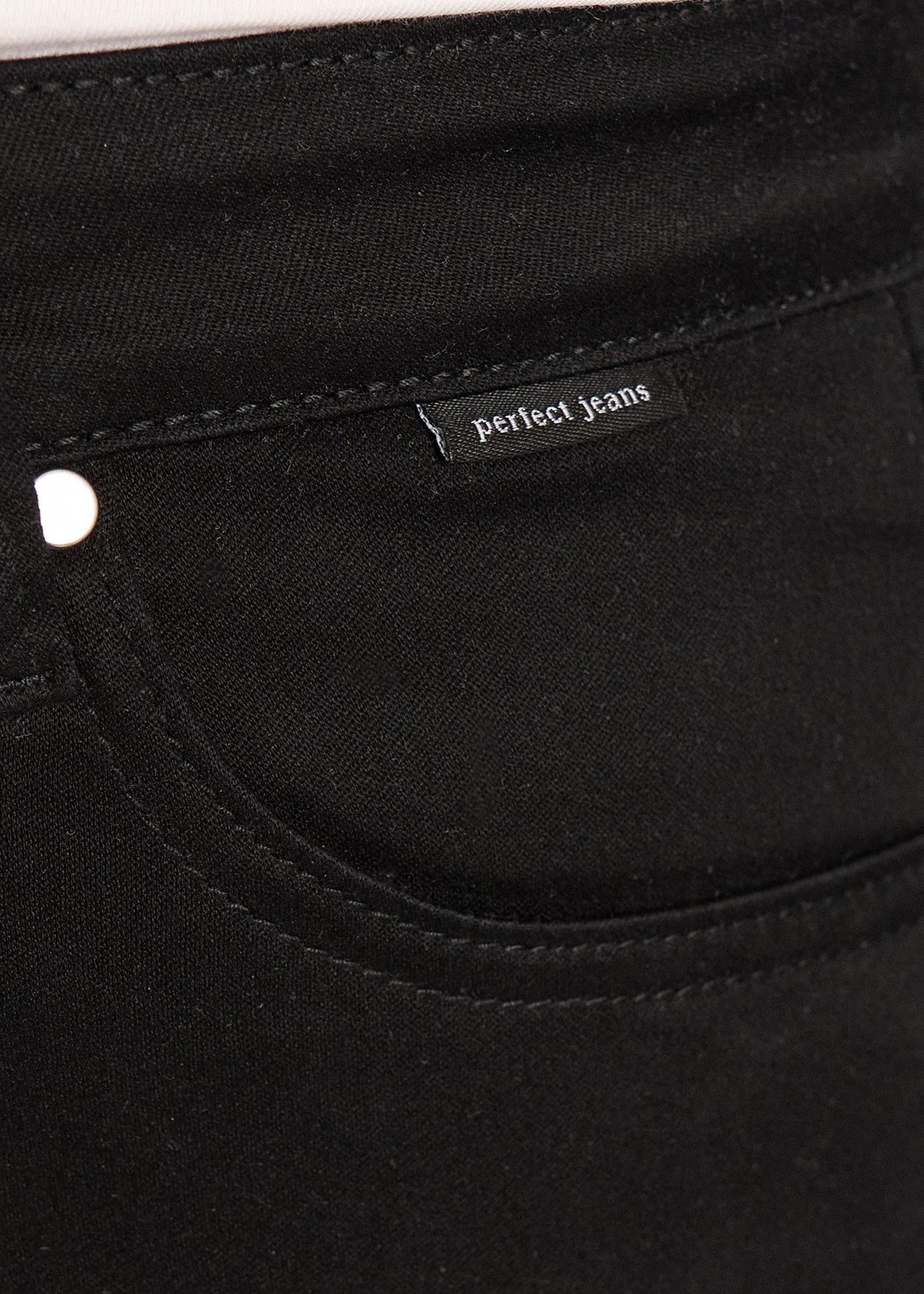 Forlommen på et par sort jeans, hvor man kan se logoet. på en plus-size model.