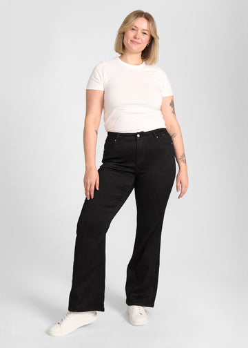Fuldt billede af model i sort bootcut jeans på en plus-size model.