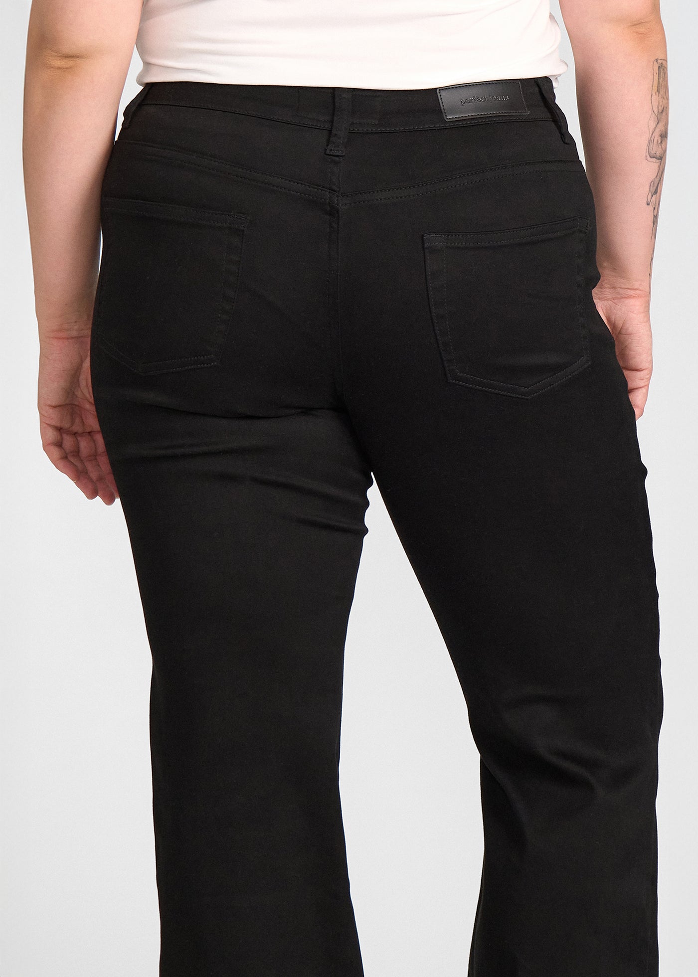 Sort bootcut jeans, modelnavn Ravens, som sidder tæt om hofter og lår med et let svaj fra knæet og ned, set bagfra tæt på for at vise detaljer. på en plus-size model.