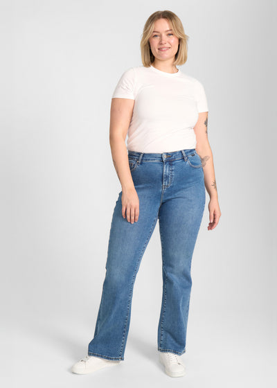 Fuldt billede af model i blå denim bootcut jeans på en plus-size model.
