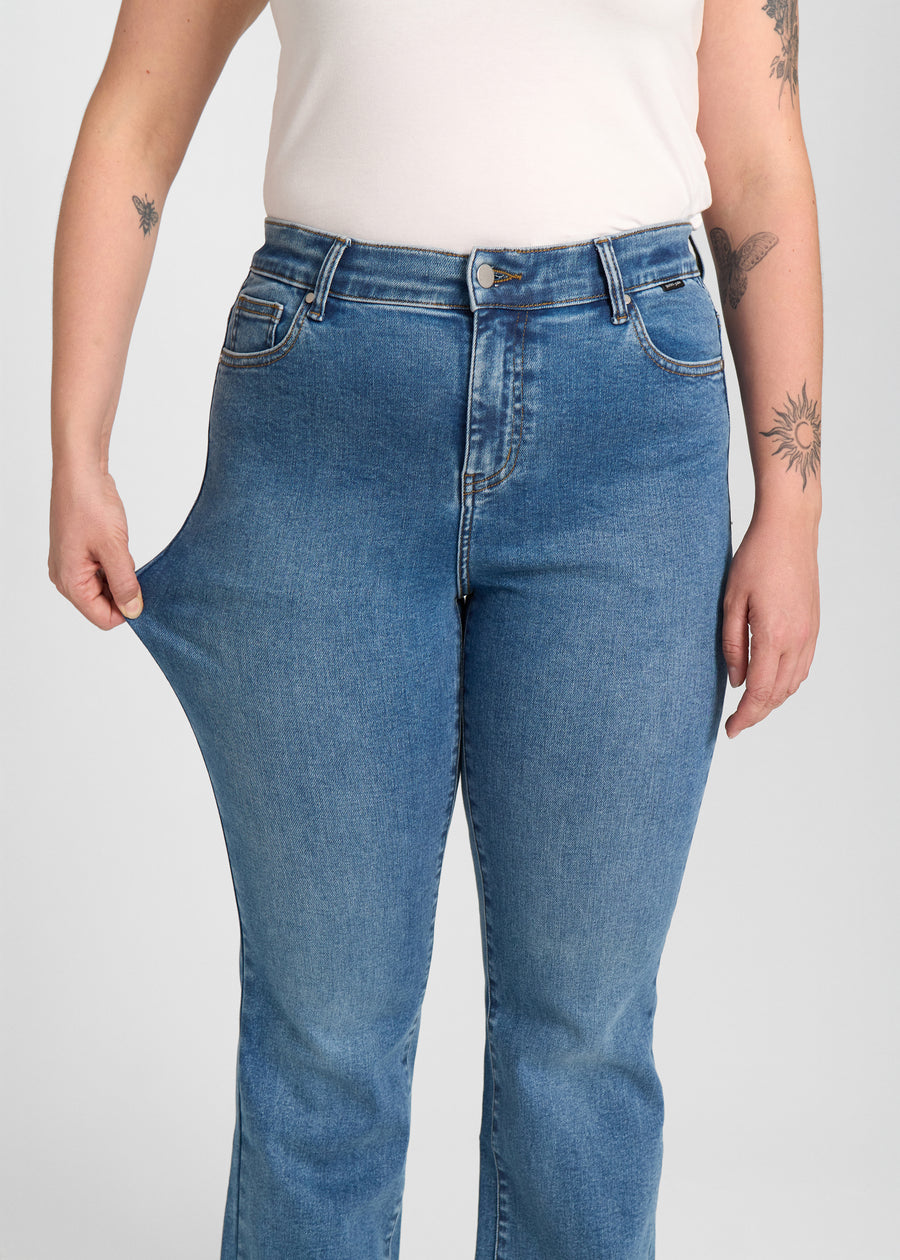 Model strækker jeansene ved låret for at vise stretch.