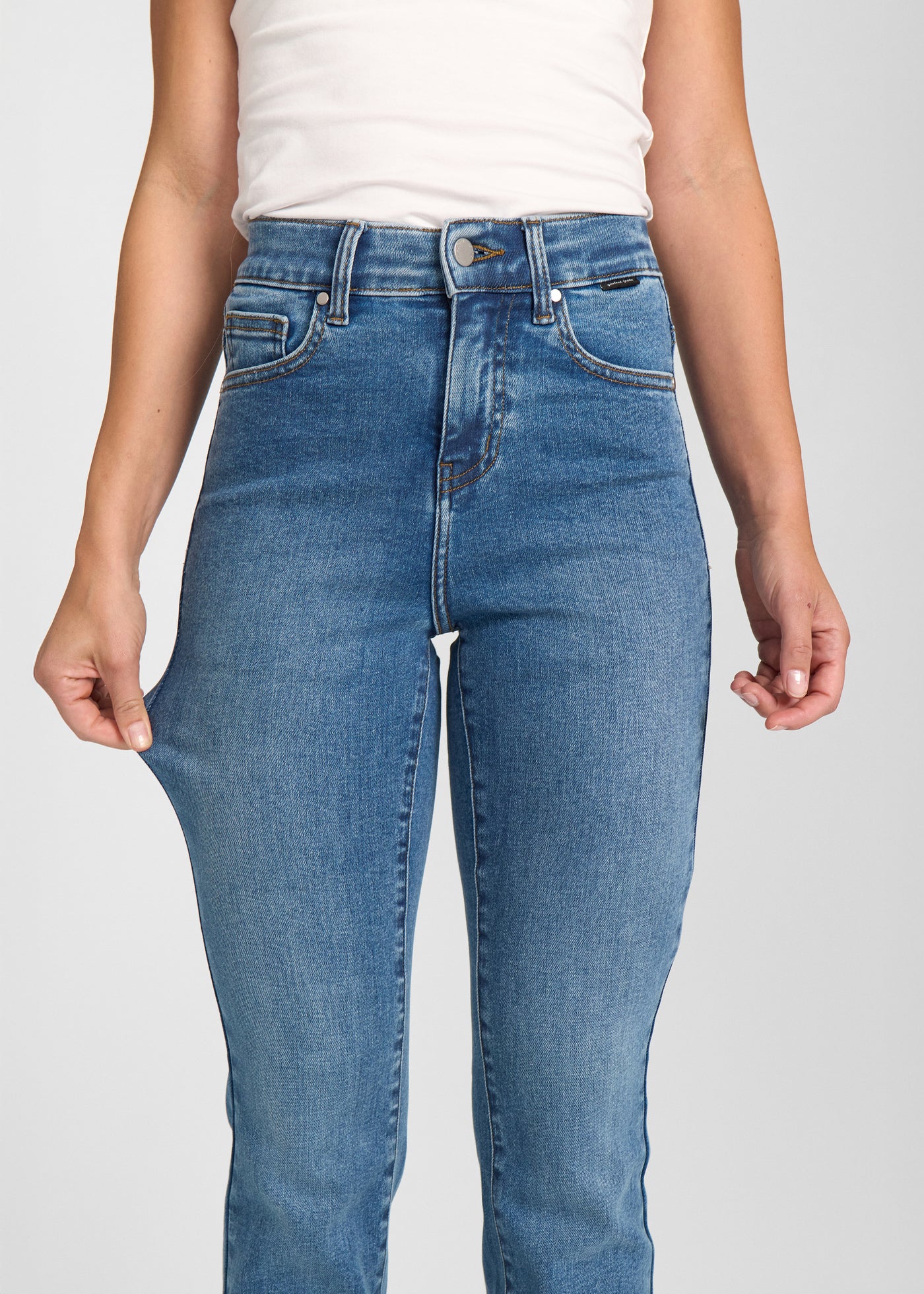 Model strækker jeansene ved låret for at vise stretch.