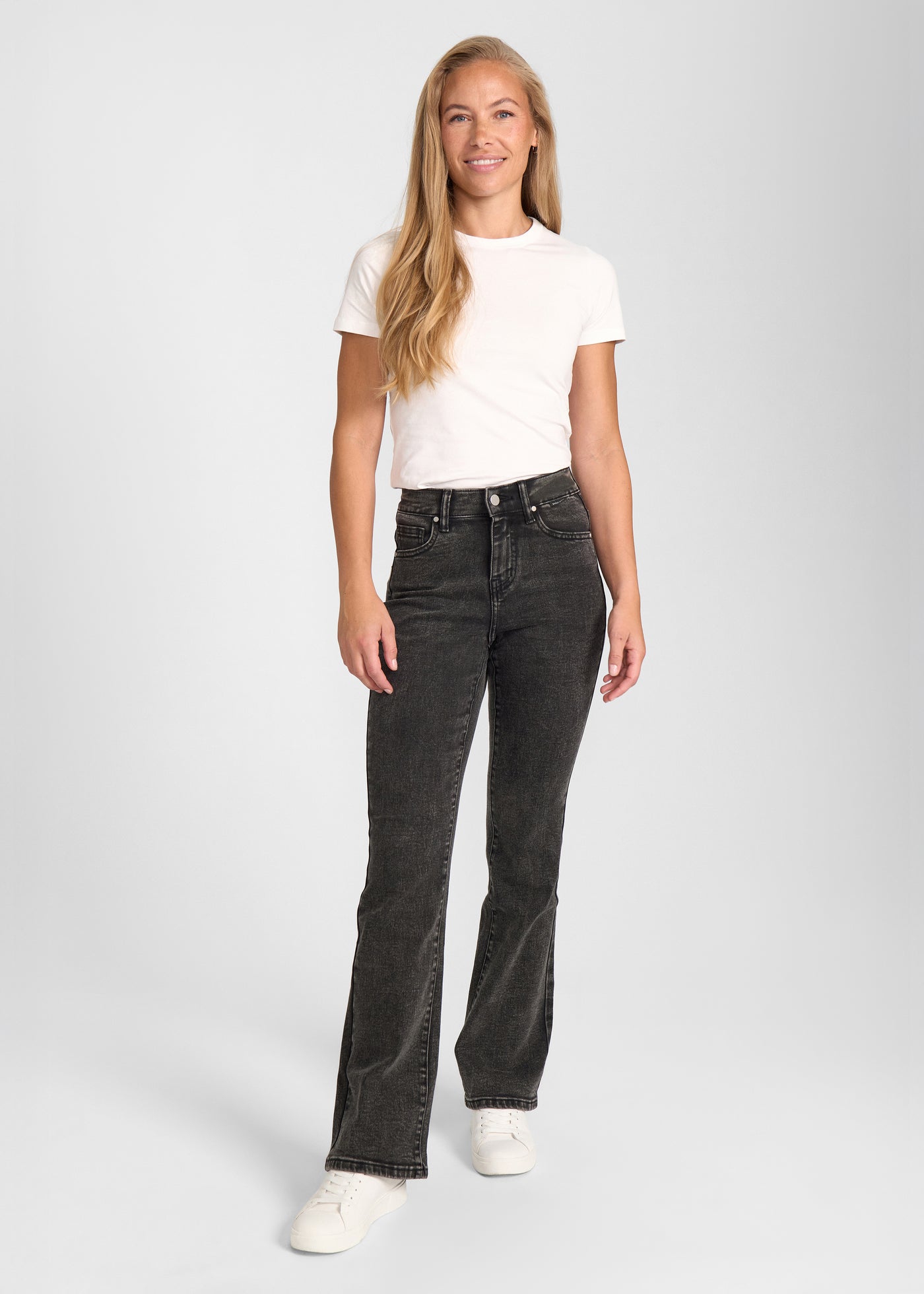 Fuldt billede af model i mørkegrå denim bootcut jeans.