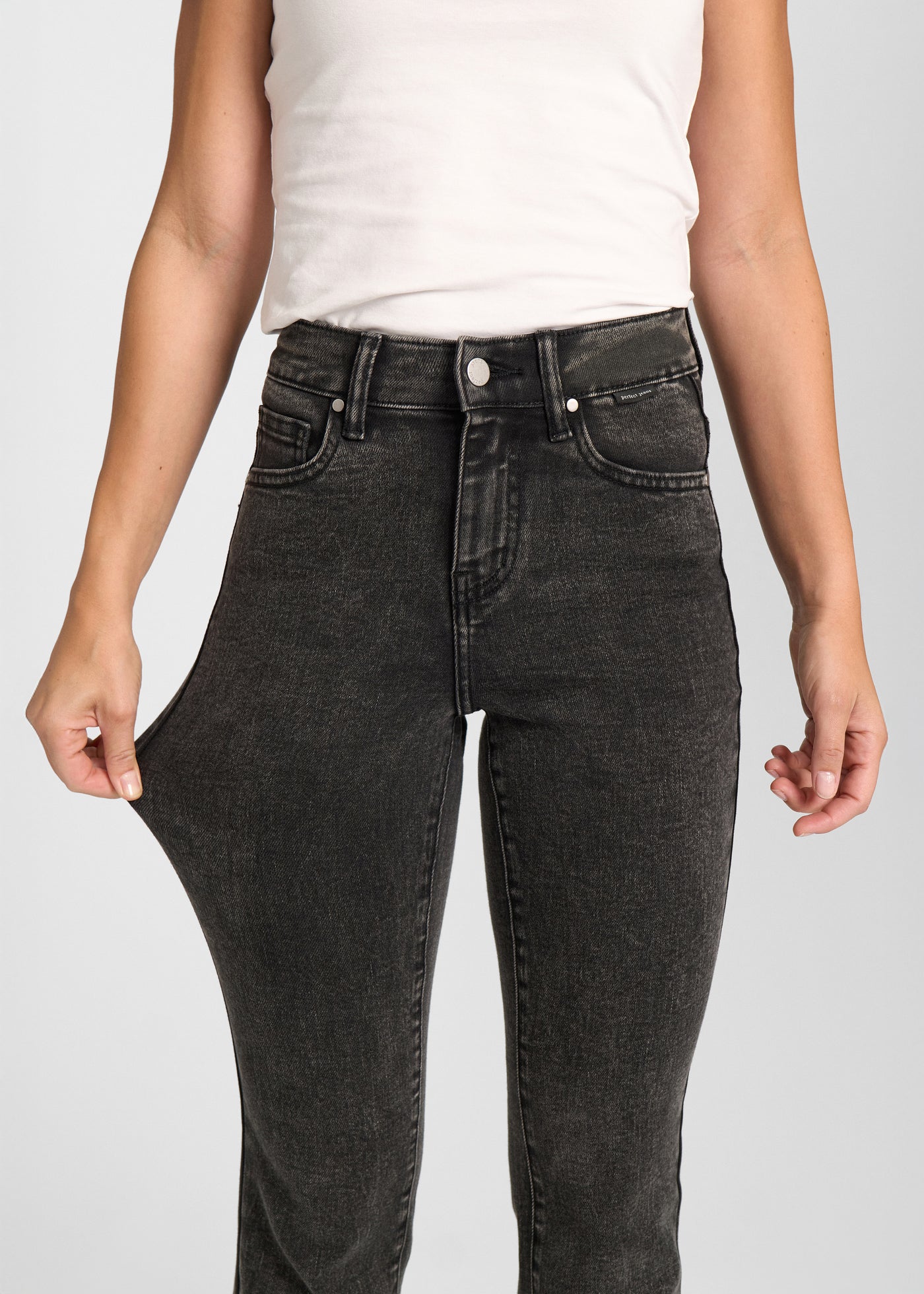 Model strækker jeansene ved låret for at vise stretch.