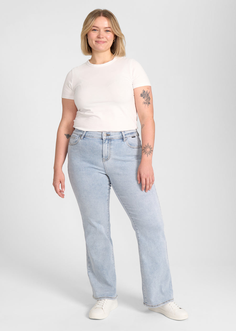 Fuldt billede af model i lyseblå denim bootcut jeans på en plus-size model.