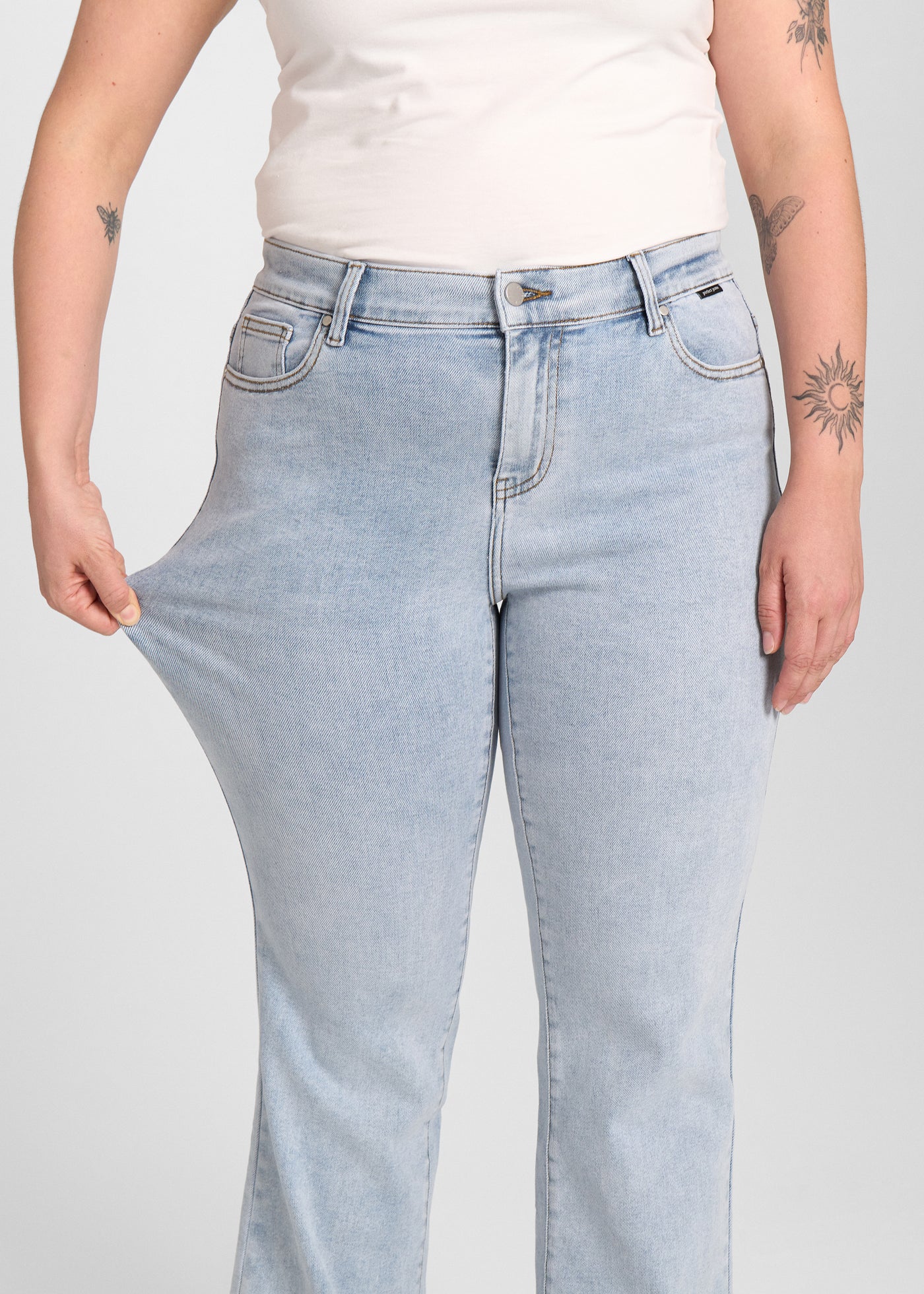 Model strækker jeansene ved låret for at vise stretch.