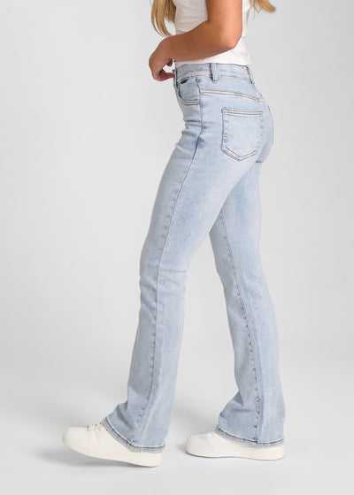 Lyseblå denim bootcut jeans, modelnavn Waves, som sidder tæt om hofter og lår med et let svaj fra knæet og ned, set fra siden på model.