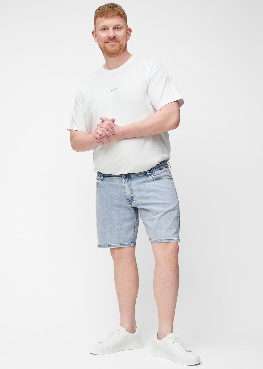 Plus-size model viser lyseblå denim shorts til mænd i farven Waves med regular pasform i bevægelse.