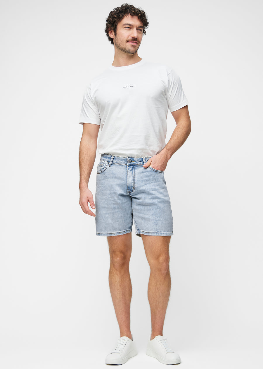 Model viser lyseblå denim shorts til mænd i farven Waves med regular pasform i bevægelse.