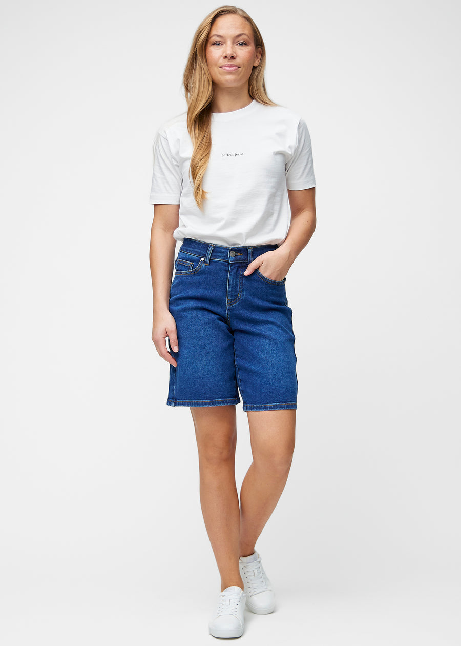 Model viser løse, mørkeblå denim shorts i farven Oceans i bevægelse og demonstrerer pasform og materiale.