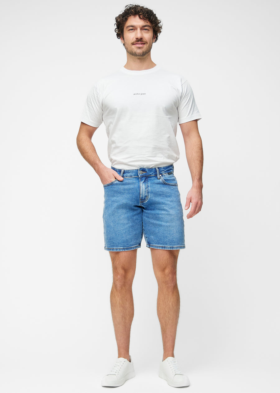 Model viser blå denim shorts til mænd i farven Rivers med regular pasform i bevægelse.