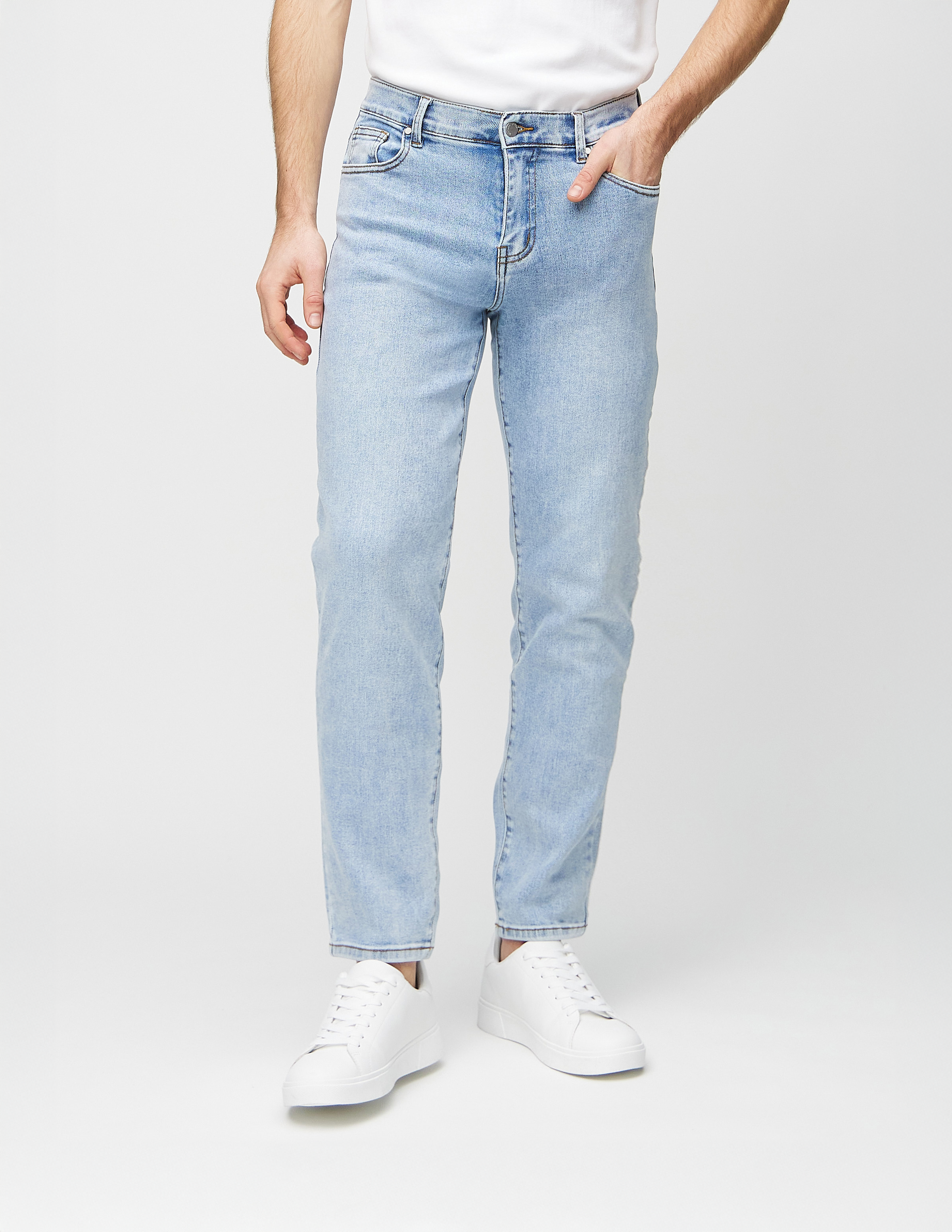 Herremodel med hånden i lommen på et par Regular denimjeans i den lyseblå farve Waves